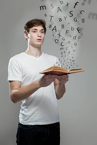 istock Young man holding a book with alphabet letters 477121344