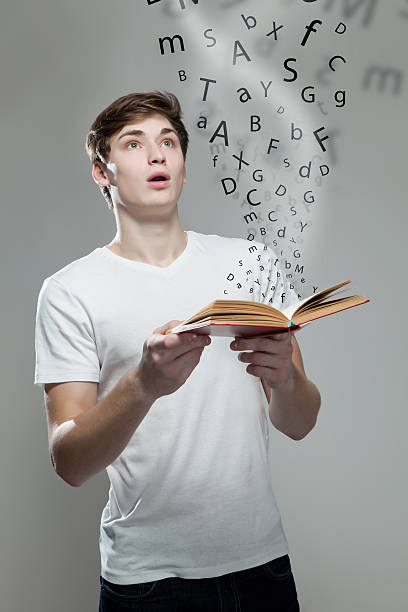 istock Young man holding a book with alphabet letters 477121346