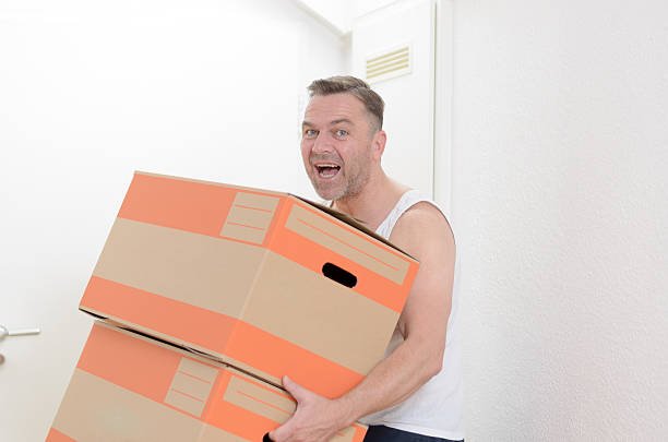 istock Man moving home carrying cardboard cartons 477130600