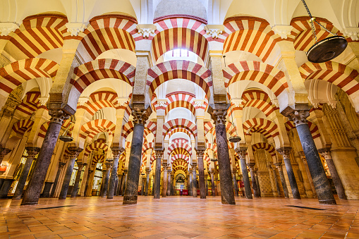 Cordoba, Spain - November 10, 2014: Visitors observe the Hypostyle Hall in the Mosque-Cathedral of Cordoba. Though now used as a Catholic Cathedral, the building s regarded as one of the most accomplished monuments of Moorish architecture.