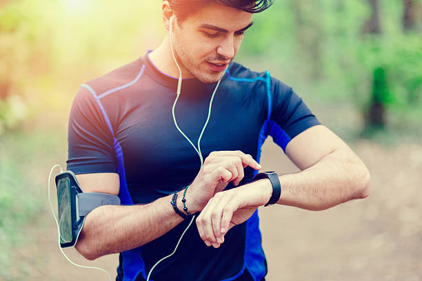 Runner in the park using smart watch Sportsman in the park checking sports stock pictures, royalty-free photos & images