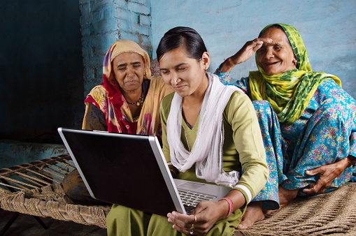 Village Women Working on Laptop with her Younger Daughter and Sitting on Charpai. The Shot is Taken using Studio Lights