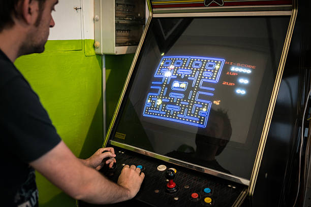 junger mann spielen videospiel-arcade - the game of operation stock-fotos und bilder