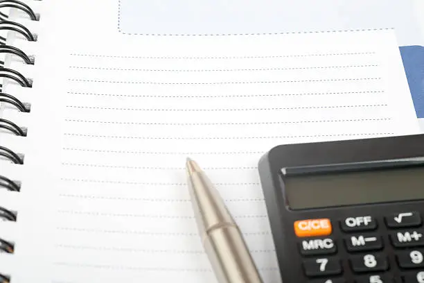 White ring-bound notebook with pen and calculator, close-up view