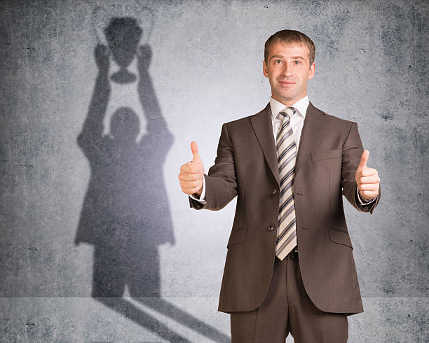 istock Businessman with shadow holding winner cup 477145588