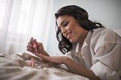 Young smiling woman having manicure treatment in bedroom.