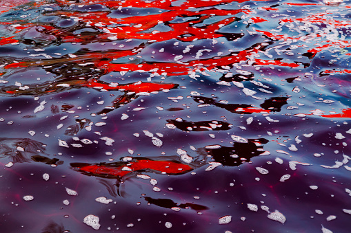 Dark red and purple water with foam on top. Abstract image of colored water.
