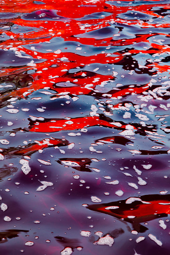Abstract vertical image of red colored water with foam. Red and purple water with foam.