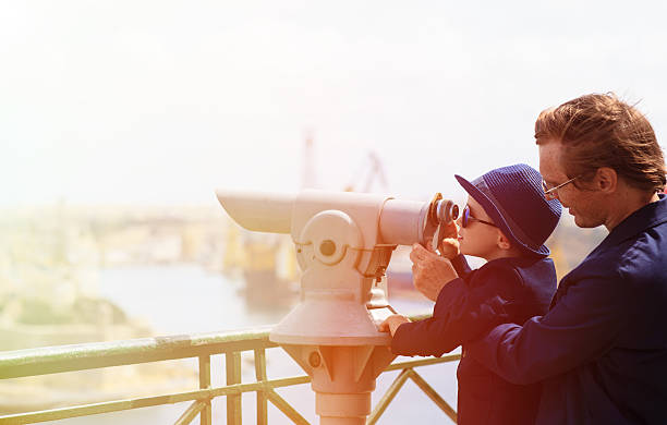 istock father and son looking through binoculars at the city 477168480