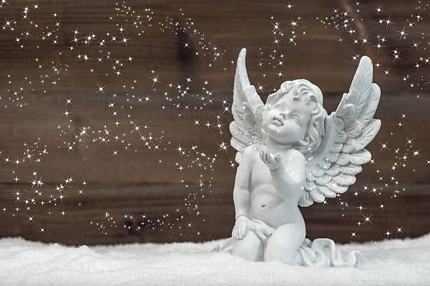istock little white angel with magic lights in snow 477169739