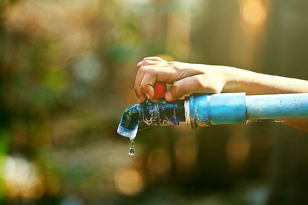 ręka trzymać na zewnątrz wody z kranu z korkiem - faucet water pipe pipe brass zdjęcia i obrazy z banku zdjęć