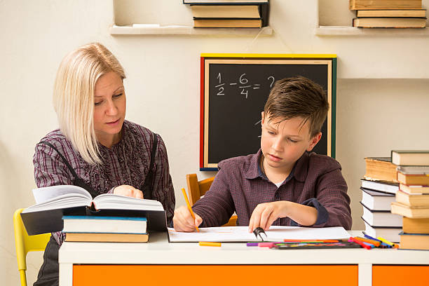 istock Schoolboy makes engaged homework with the tutor. 477180854