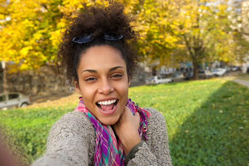 Selfie portrait of a happy young woman outside in the park
