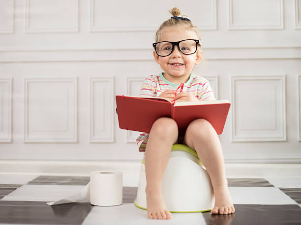 Baby girl on potty with notebook stock photo