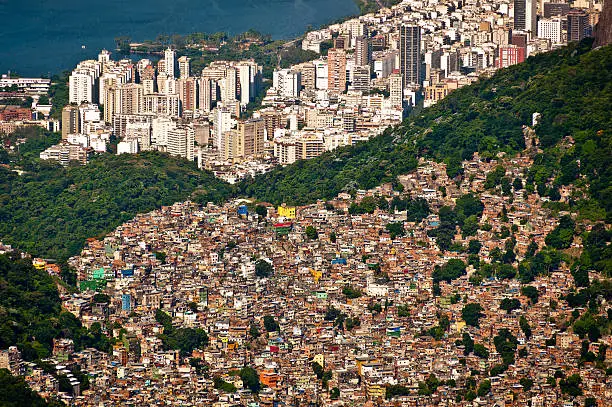 Aerial view of Favela da Rocinha, Biggest Slum in Brazil on the Mountain in Rio de Janeiro, and Skyline of the City behind.