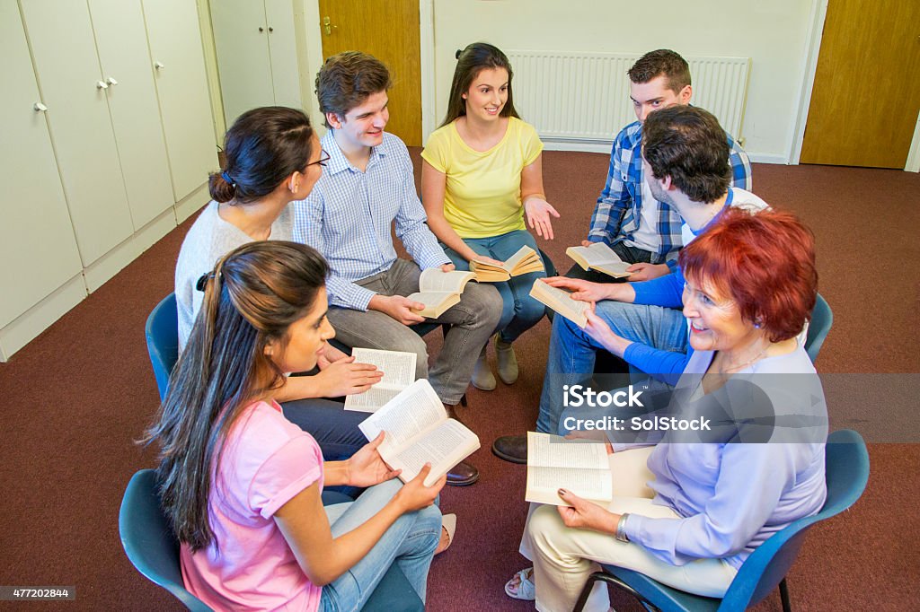 Group Reading A group of seven community members sit in a circle together with books in their hands chatting about the story. They are all discussing it with eachother and are wearing casual clothing. 2015 Stock Photo