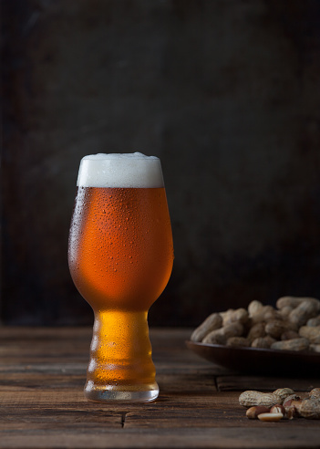 a glass of beer and plate of peanuts