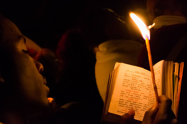 Timkat celebration in Ethiopia Gonder, Ethiopia - January 20, 2012: priest holding a candle in the night and reading a book written in the old language of the church, called Geez, during the Timkat holiday, the important Ethiopian Orthodox celebration of Epiphany. ethiopian orthodox church stock pictures, royalty-free photos & images