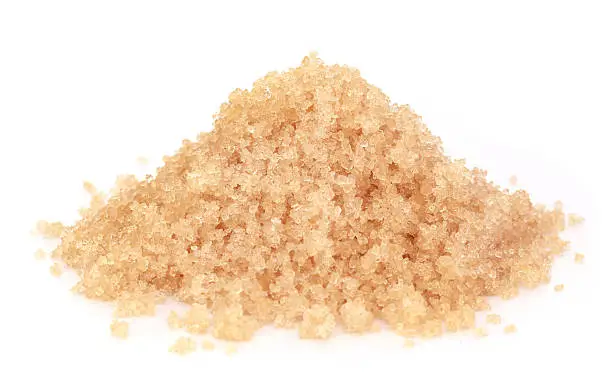 Coarse crystals of brown sugar over white background