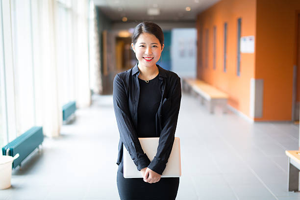 Asian college student standing with a laptop