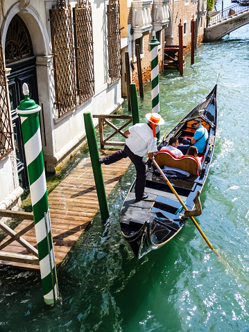 Venice, Italy - September 13, 2014: Venetian gondolas with tourist sail in the canal in Venice. Permissions for gondolas are very expensive and limited.