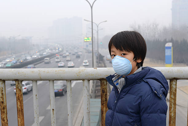 アジアの少年着用くわえるマスクと空気汚染（北京） - 大気汚染 ストックフォトと画像