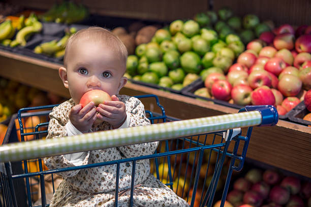 grocery shopping with baby Cute baby in a shopping cart eating an apple supermarket family retail cable car stock pictures, royalty-free photos & images