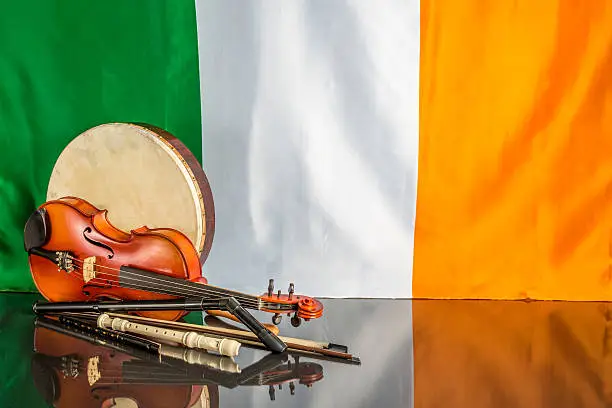 A collection of traditional Irish musical instruments on a black table with a Itish flag back ground