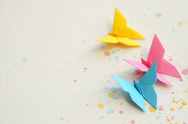 istock Three colorful butterflies on white wooden background splashed with paint 477239324