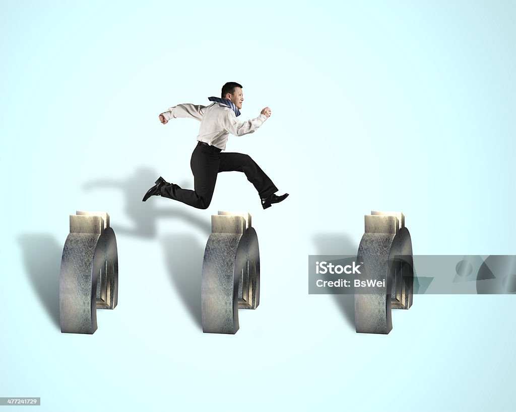 businessman jumping over euro obstacles businessman jumping over euro obstacles isolated in blue background 3000 Meter Stock Photo
