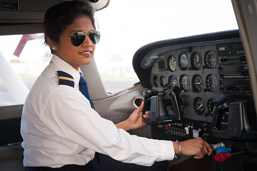 A female pilot at the controls of a Cessna aircraft. She is dressed in her pilots uniform.