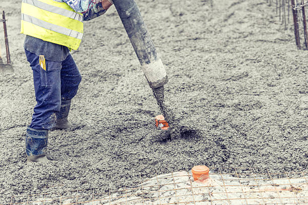 worker pouring concrete, directing the pump and working in foundation Construction worker pouring concrete, directing the pump and working in foundation directing photos stock pictures, royalty-free photos & images