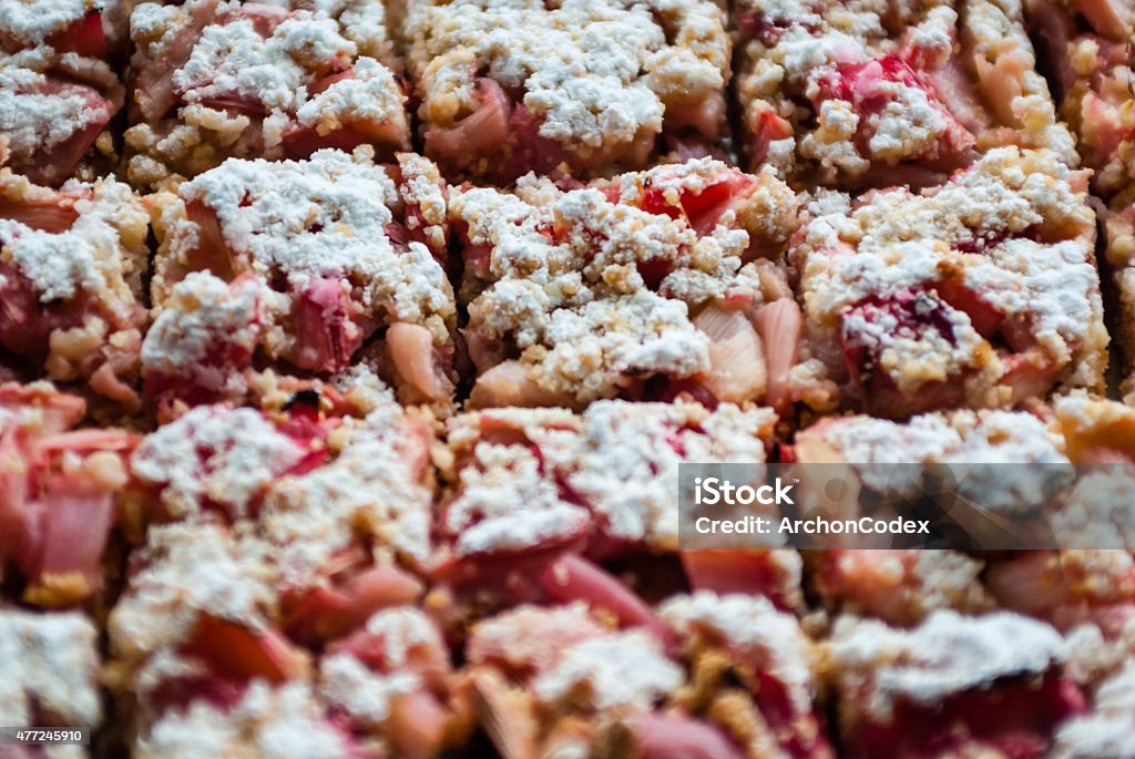 Cut rhubarb cake sprinkled with powdered sugar Close-up macro of fresh rhubarb cake pastry sprinkled with white powdered sugar icing, cut into squares with focus on middle piece. Rhubarb Stock Photo