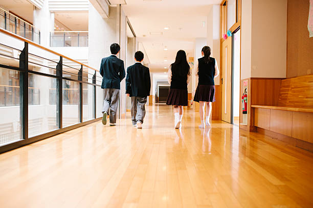 Japanese high school. Four students walk through corridor, rear view stock photo