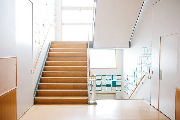 A view of a Japanese high school. The first floor staircase and corridor in a Japanese high school. Contemporary architecture, interior view, horizontal composition. Nobody. 