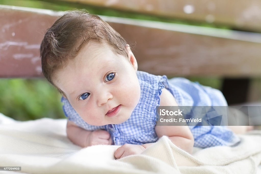 Hermosa niña bebé relaja en su estómago en banco de jardín - Foto de stock de Aire libre libre de derechos