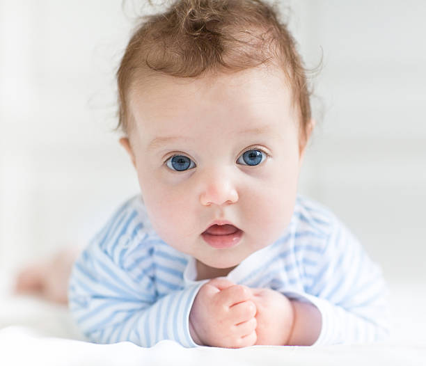 istock Funny baby with big blue eyes playing on her tummy 477256703