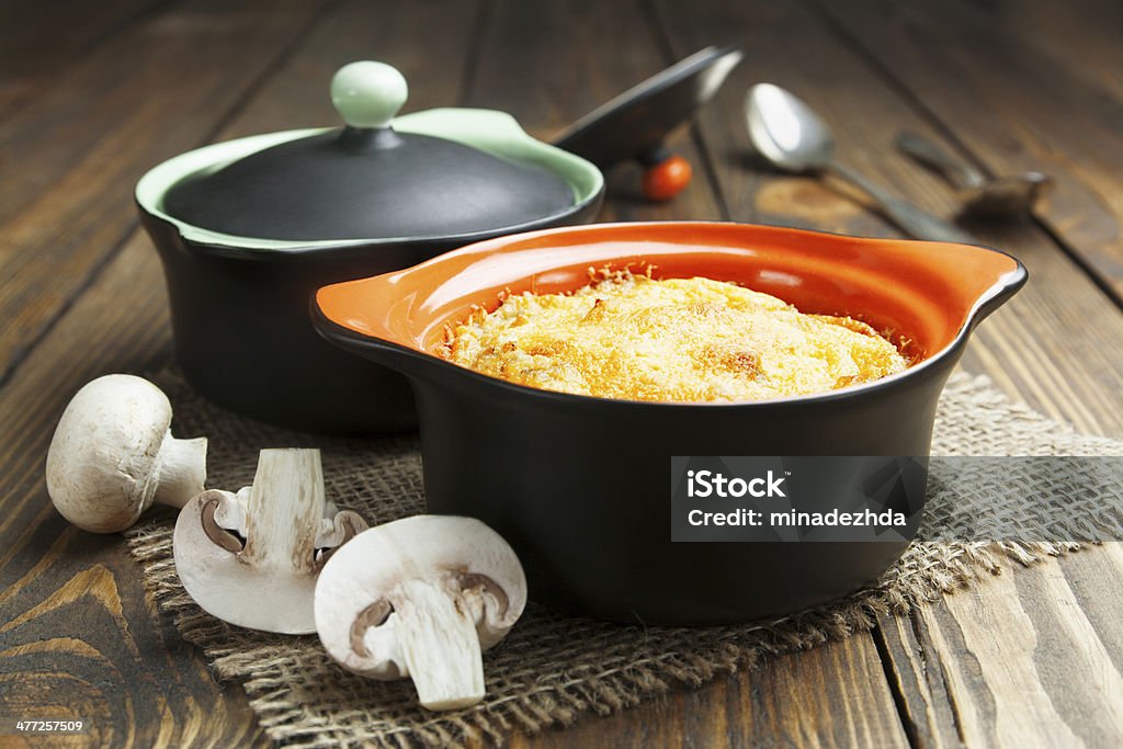 Mushroom Casserole in the pot Casserole with mushrooms and cheese in the pot on the table Baked Stock Photo