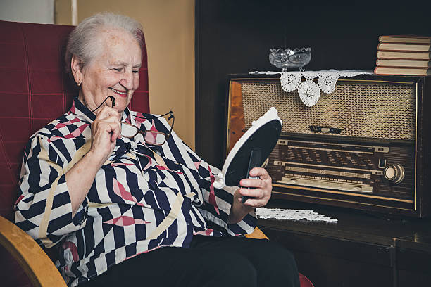 istock Senior woman smiling and looking at old photo frame 477257904