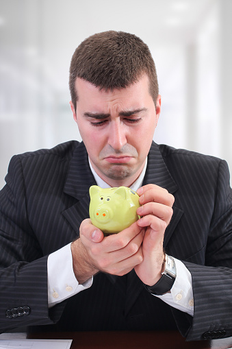 Sad Businessman with his piggy bank in office