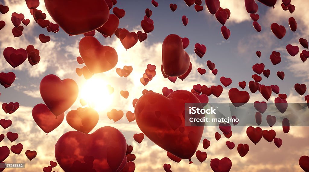 Balloon Hearts A11 A group of heart-shaped balloons flying through the air on a cloudy sky background. The hearts appear transparent in a red hue and have a slightly marbled surface. Heart Shape Stock Photo