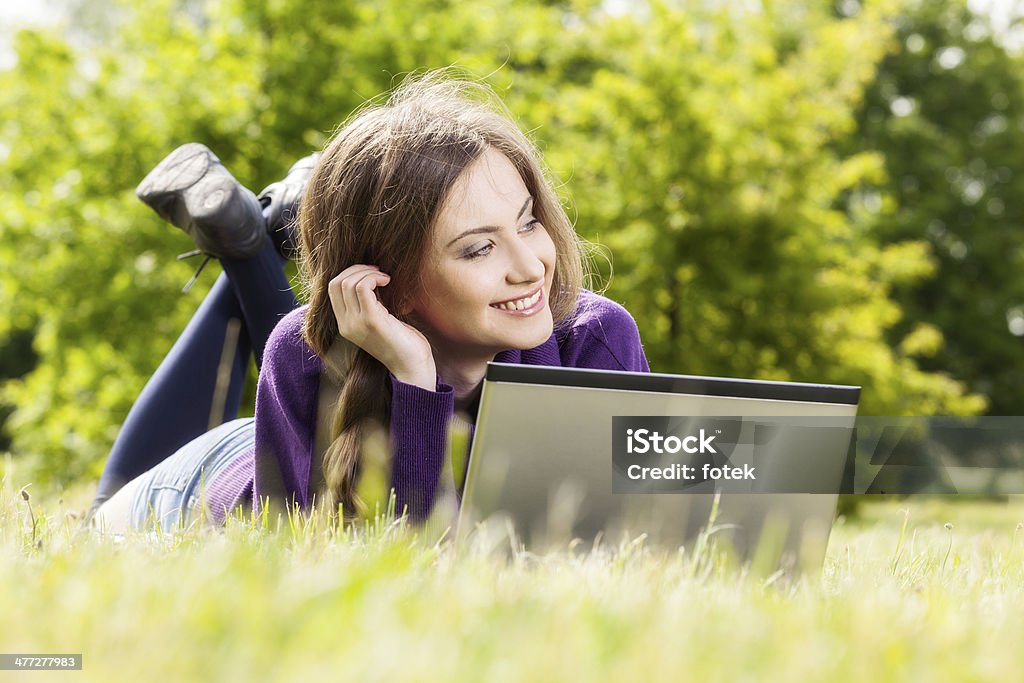 Mujer joven usando una computadora portátil en el parque - Foto de stock de Acostado libre de derechos