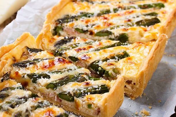 Delicious home made asparagus savory tart with pecorino and bacon on old wooden background.  Selective focus.