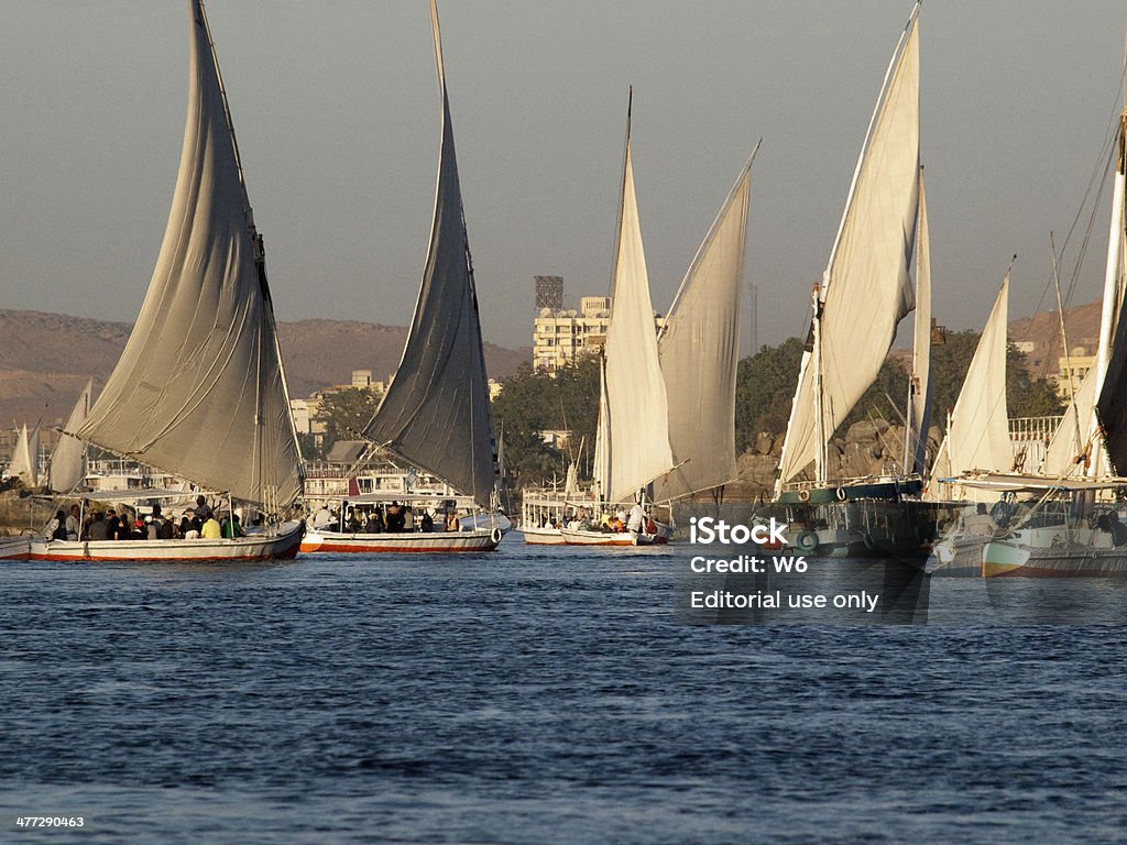Feluccas in River Nile Aswan, Egypt - December 23, 2010: People on the Felucca boats down the Nile River at Aswan in Egypt. A cruise on a Felucca is a popular activity for tourists visiting Aswan. Adult Stock Photo
