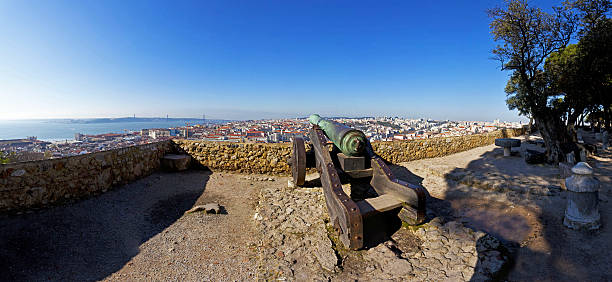 Sao Jorge (St. George) Castle in Lisbon, Portugal. Old Bronze cannon and a view of Lisbonâs Baixa (downtown) District and river.
