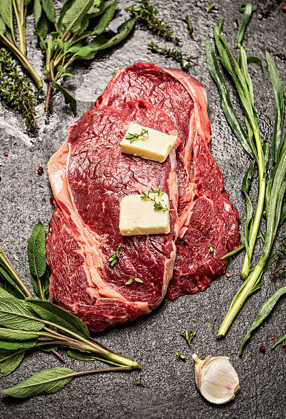 Raw ribeye steak with fresh herbs variety and butter, ingrediets
