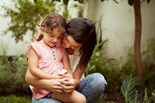 Mother and daughter looking at flower in garden