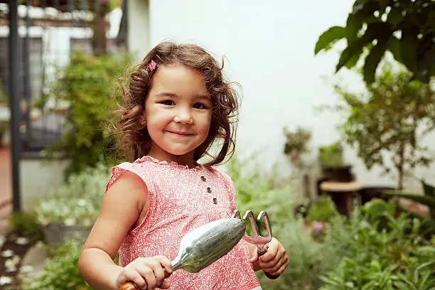 Portrait of little girl with gardening tools in garden