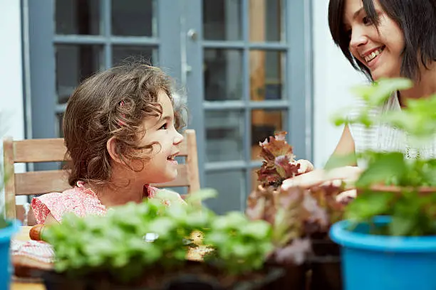 Mother and daughter potting plants at table