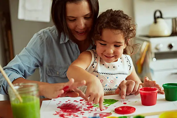 Mother and daughter painting together in kitchen